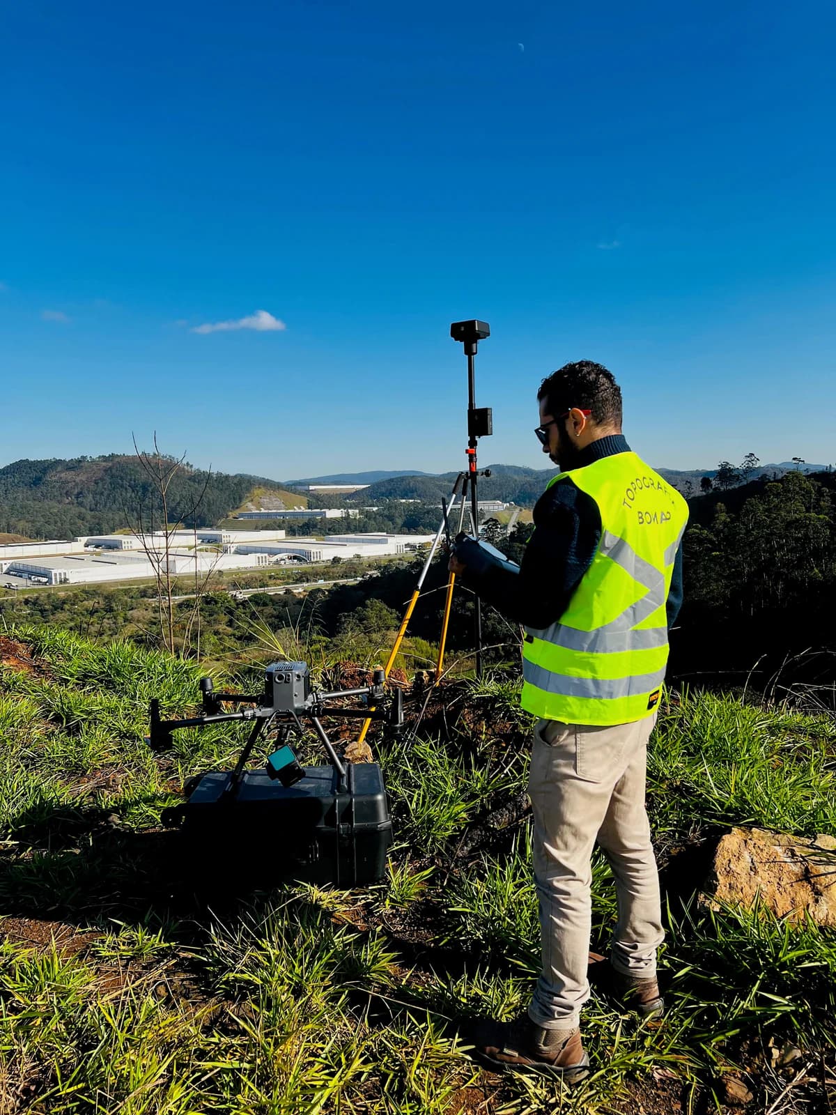 Drone pousado com base GNSS em primeiro plano, vale ao fundo